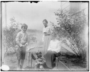 Two women and two young boys in the garden at the side of a house