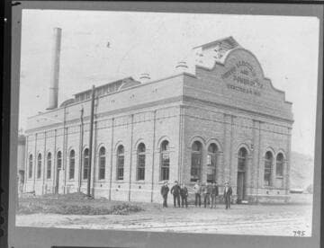 A group of men standing in front of the Santa Barbara Steam Plant