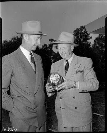 Two men holding Edison's One Millionth Meter at the job site