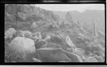 Men on horseback on mountain trail with pack horses
