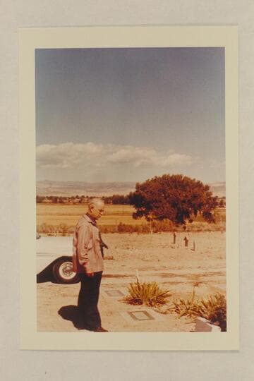 Dock Marston at the grave of Frank V. Goodman.  The wooden markers in background are the graves of Nat Galloway and his wife