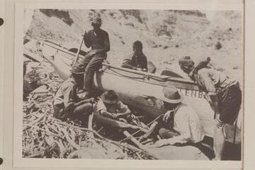 Part of the Eddy crew examining the hole punched in the "Dellenbaugh" while lining the 5th Rapid in Cataract Canyon.  Upper:  Holt Calloway, Lower:  Felton with head down at left; McGregory; Eddy; Galloway; Marshall