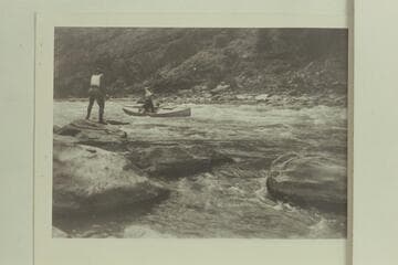 Identified by Emery Kolb as being in Red Canyon on the Green River.  Note the figure on shore is wearing the dangerous choke-bored breeches and heavy boots.  The boats were frequently stuck in the rocks through Red Canyon