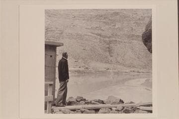 Harry Aleson stands at the gauge on the left bank at Lees Ferry and looks across the river to the old Spencer Mining buildings