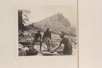 Moulty Fulmer toasting bread at Nancoweap Camp.  Others figures are Nevills and Masland