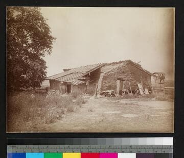 Adobe house with wood plank extension and tile roof