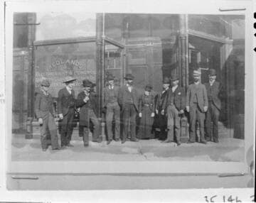 A group portrait of the officers and the office staff of the Redlands Light & Power Company standing in front of their company office on Orange Street