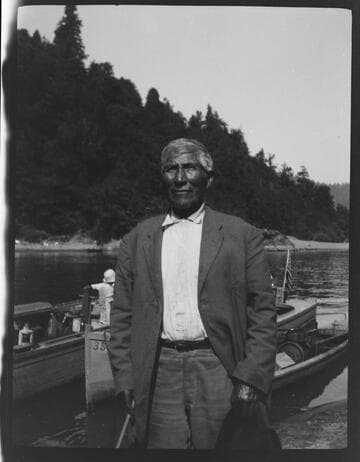 An unidentified Native American man, with boats behind him