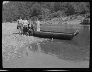 Grace Nicholson (seated on canoe) with Native American man and two women