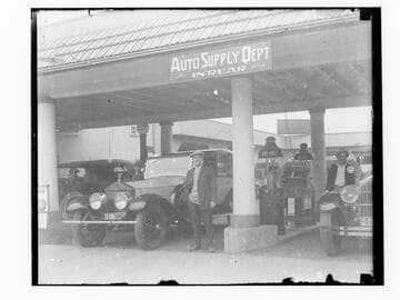 Men standing next to cars at gas station