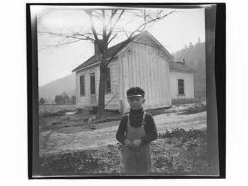 Little boy and dog in front of a small house