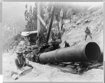 Skilled workmen install the last segment of German-made penstock pipe at Big Creek #1 Hydro Plant