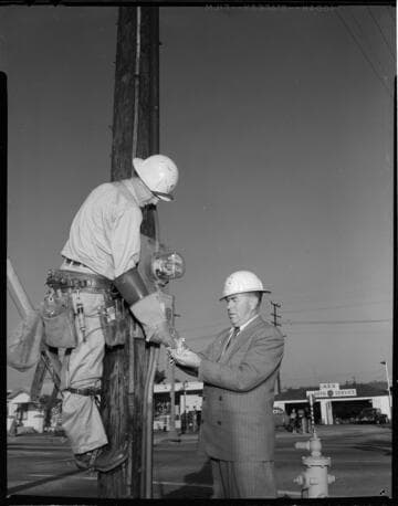 Lineman on metered pole clearing streams from conductors