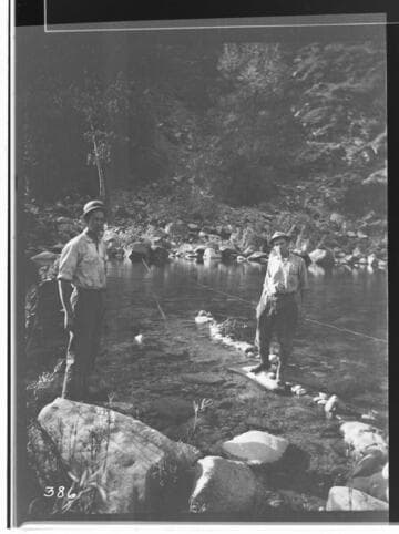 Two men standing on rocks in a pond