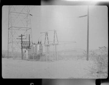 Small distribution substation near transmission tower in desert