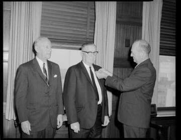 Executive pinning award on lapel of another man