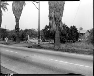 Gate to a small wooden farm  house as seen from across a road