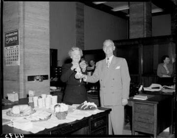 Man pinning corsage on lady in office