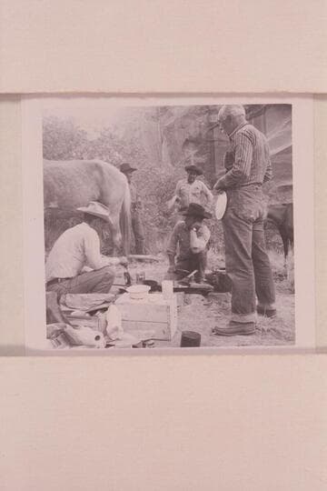 Masland waits for pancakes at camp at head of middle fork of 73.  Tom Daly is cooking, Tobe Owl is back of the horse and Dan Lehi looks at Buster Ordiway