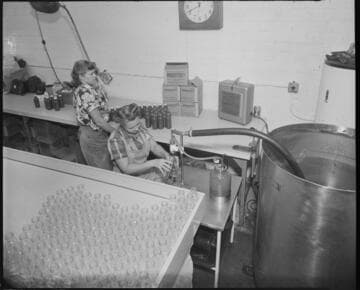 Ladies filling and sealing bottles with sauce for packaging
